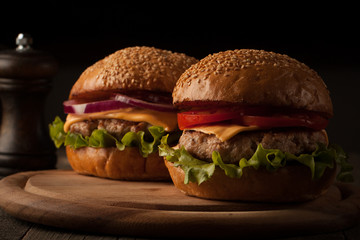 Home made hamburger with beef, onion, tomato, lettuce and cheese. Fresh burger closeup on wooden rustic table with potato fries, beer and chips.