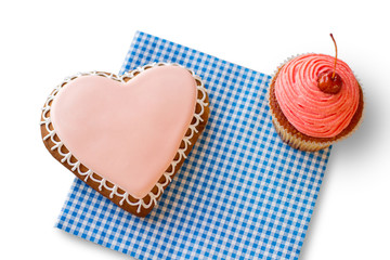 Heart cookie and pink cupcake. Pastry on blue checkered napkin. Small holiday for loved ones. Find joy in the ordinary.