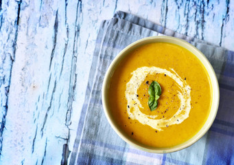 Bowl with pumpkin soup and copy space. Cream soup on a rustic wooden table.