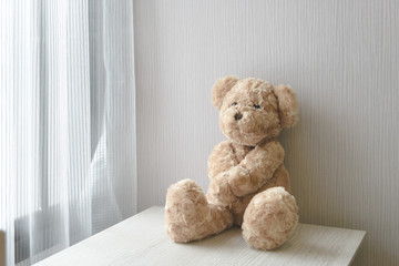 Teddy bear sitting on wooden desk in room with copy space