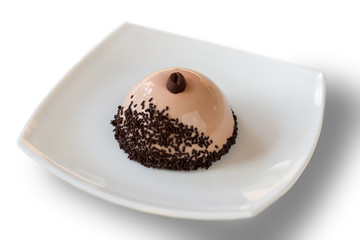Dome shaped dessert on plate. Dish with mirror icing. Coffee mousse cake with decoration. Plain design and good taste.