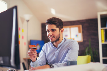 Man paying with credit card on computer at home office