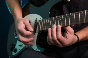 Fototapeta na wymiar Young man playing electric guitar on dark background