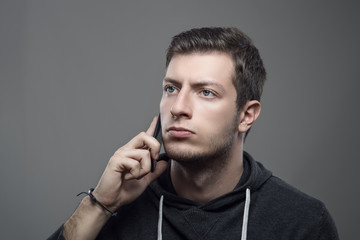 Portrait of young sporty serious man talking on the phone looking away
