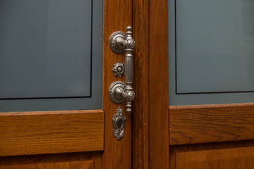 The old, metal doorhandle of a wooden door