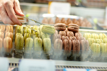 Taking out pistachio macaron from showcase .