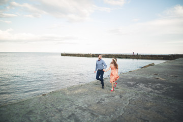 Beautiful loving couple, pride with long dress walking on pier