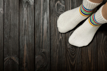 Fototapeta na wymiar Legs knitted white woolen socks on wooden dark background..