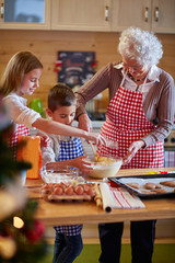 children and grandmother preparing Xmas cookies.