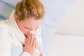 frau liegt mit schnupfen im bett