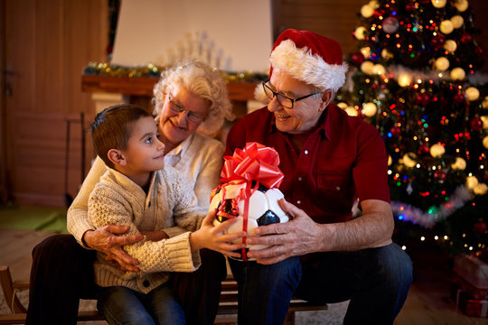 Grandparents Giving Gifts Grandson At Christmas Eve.