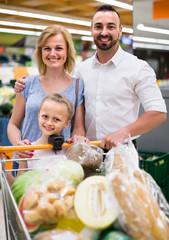 Portrait of  family standing with full cart in supermarket