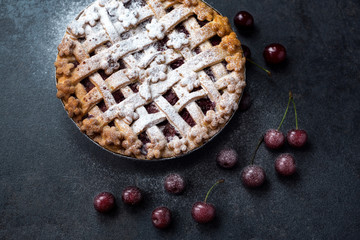 homemade cherry pie with powdered sugar and fresh cherry.