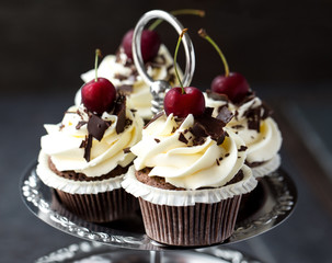 Beautiful chocolate cupcakes with white cream and cherry   .