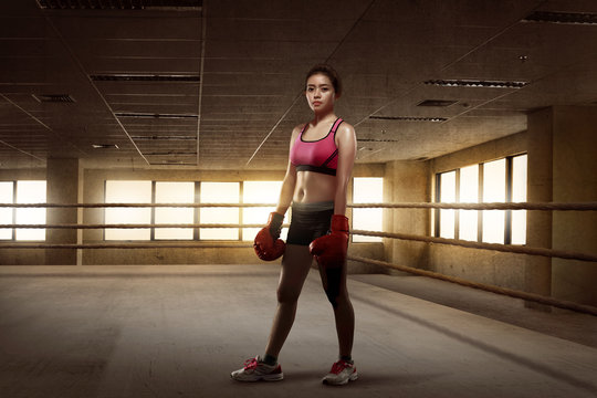 Beauty asian girl boxer with red gloves standing in the boxing ring