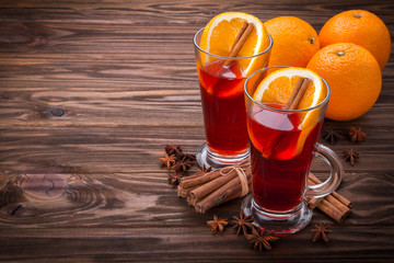 Glass with mulled wine, spices and fruits on wooden background