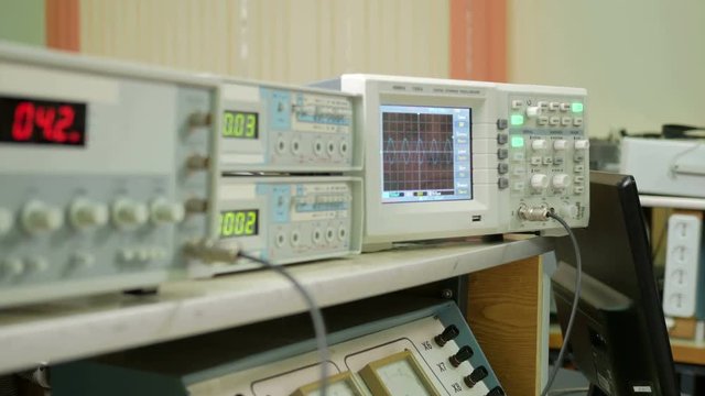 Equipment for measuring electrical signals is in the physical laboratory. The scoreboard lit instrumentation data. Oscilloscope and a pulse generator working together.
