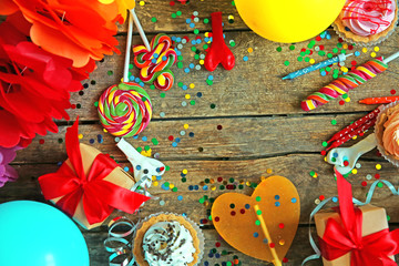 Birthday party objects on wooden background, top view