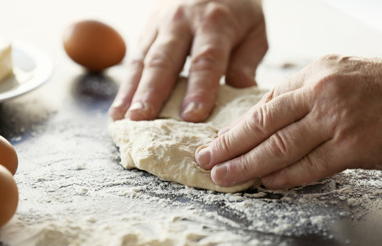 Male hands kneading fresh dough on table