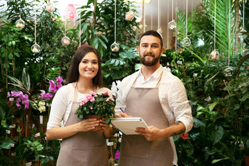 Florists with notebook, pen and azalea flower in greenhouse