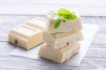 White chocolate with nut on a white wood background. Copy space