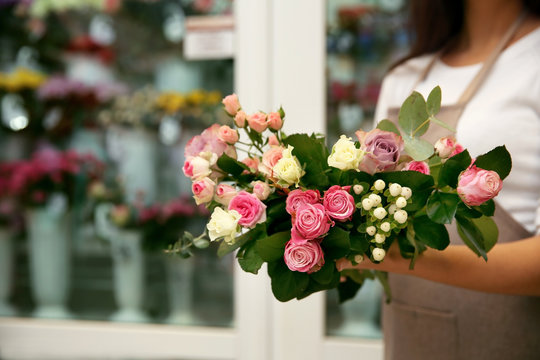 Young florist holding bouquet of flowers, close up view