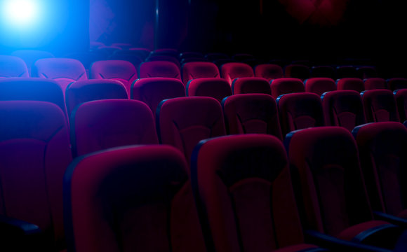 Dark film theater with projection light and empty seats