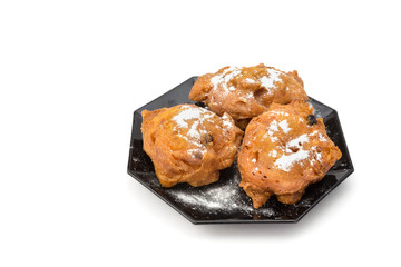 Three sugared fried fritters or oliebollen on saucer