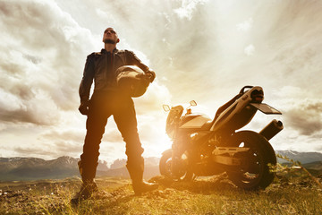 Biker with motorcycle on mountains backdrop