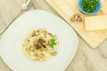 Risotto with mushrooms, parmesan cheese and parsley on a wooden background