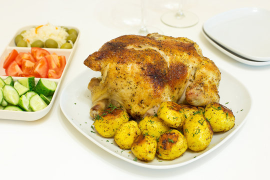 Roasted chicken and potatoes on white plate