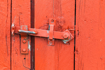 Old metal latch on red wooden door