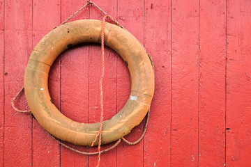 Lifebuoy hanging on red wooden wall