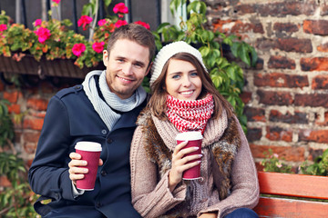 Young couple sitting on bench with coffee © Kalim