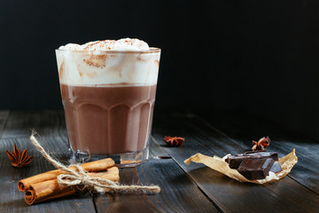 hot chocolate with whipped cream and cinnamon on the black table