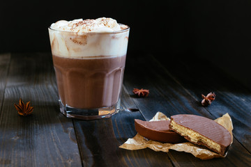 hot chocolate with chocolate wafers on the black table