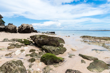 Fototapeta na wymiar Small rocks scattered on beach sand close up. Beautiful ocean landscape, amazing sky. Bali, Indonesia.