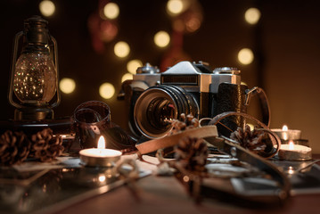 Fototapeta na wymiar Christmas composition old vintage camera, candles, flashlight on a dark wooden table