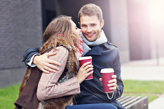 Young couple sitting on bench with coffee
