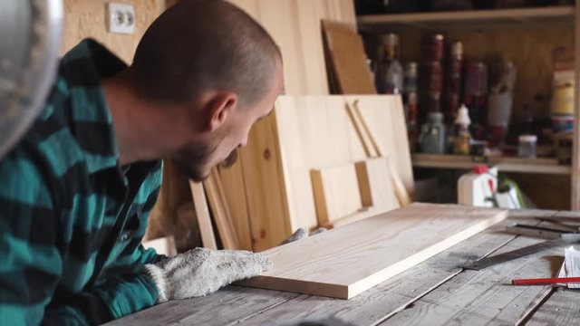Focused bold carpenter with vintage moustache at work with wooden plank