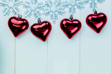 Snowflakes and heart ornaments hanging on white wood background
