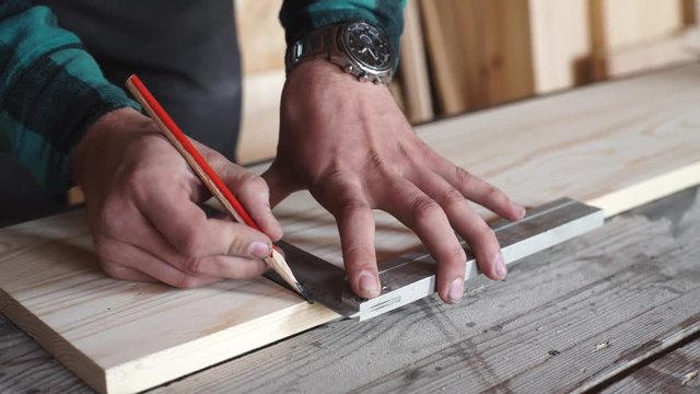 Male hands with ruler and pencil closeup. Professional carpenter at work.