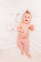 baby girl in knitted pants lying near her toy bunny