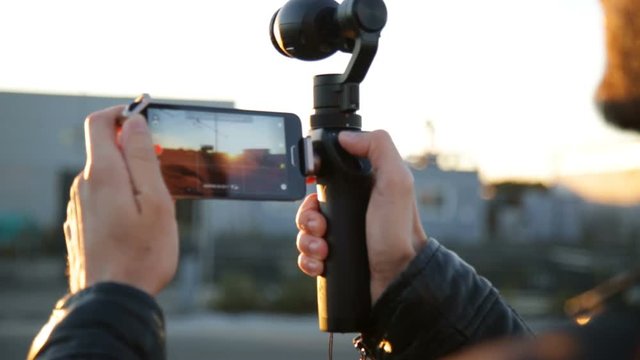 Young boy is taking video footage with a gimbal camera at the Train station