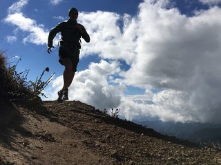 Backlit shot of male runner on mountian top trail
