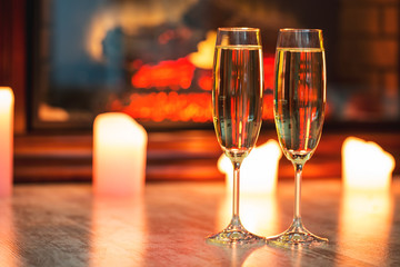 Beautiful two glasses of champagne standing on the table in the background of a blurred room with a decorated Christmas tree and candles. Soft focus. Shallow DOF