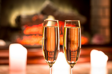 Beautiful two glasses of champagne standing on the table in the background of a blurred room with a decorated Christmas tree and candles. Soft focus. Shallow DOF