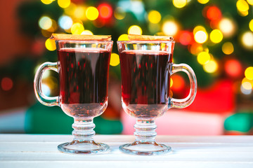 Beautiful Two glasses of mulled wine on bokeh background decorated Christmas tree. The idea for postcards. Soft focus. Shallow DOF