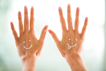 Closeup woman beautiful hands with long fingers applying moisturising and soothing cream on skin. Funny smiling faces, emoji.