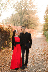 Young couple of pretty girl and man walk outdoors in park